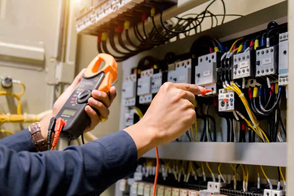 Electrician engineer work tester measuring voltage and current of power electric line in electical cabinet control