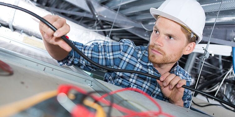 Man repairing electrical wiring on the ceiling